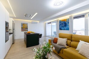Un salon moderne avec un canapé, un coin repas avec une table et une cuisine équipée.