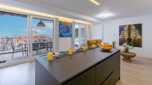 A modern kitchen with a large island, breakfast bar, and dining area with a view. - Fidalsa Penthouse Amazing View (Alicante)