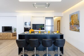 A modern kitchen with a central island, bar stools, and a painting on the wall.