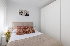 A bedroom with a bed, a nightstand, a lamp, a plant, and two wall art pieces. - Fidalsa Penthouse Amazing View (Alicante)