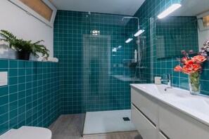 A bathroom with teal tiles, a shower, a sink with a mirror, and a potted plant. - Fidalsa Penthouse Urban Sea View (Alicante)