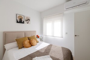 A bedroom with a bed, pillows, a blanket, wall art, and an air conditioning unit. - Fidalsa Penthouse Urban Sea View (Alicante)