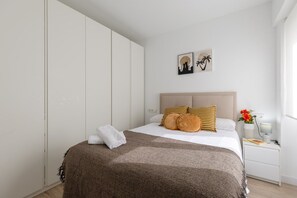 Ein ordentlich eingerichtetes Schlafzimmer mit Bett, Nachttisch und Kleiderschrank.