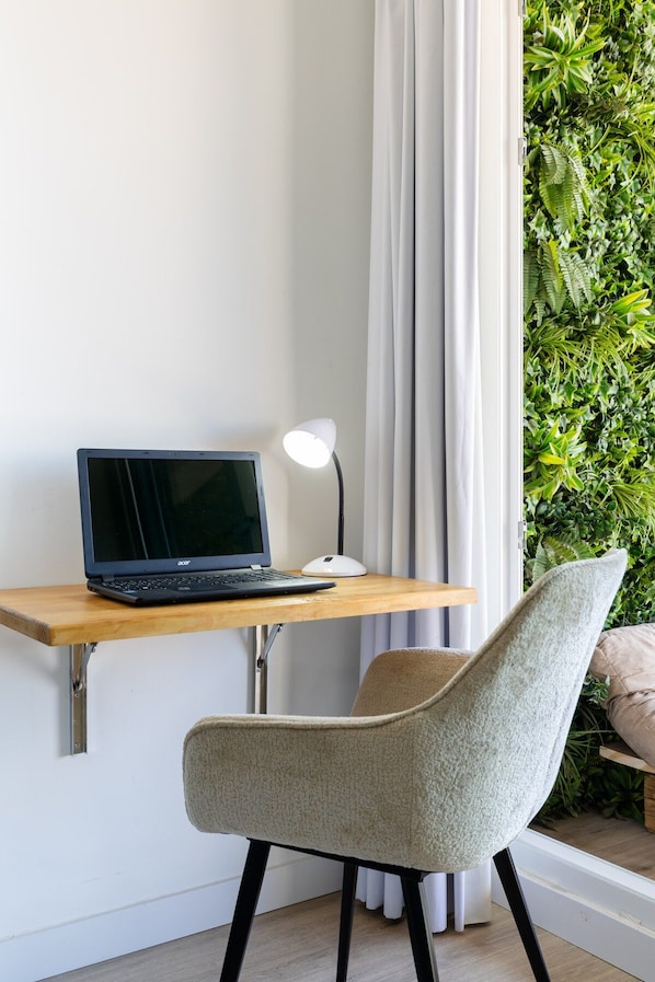 A laptop on a wooden desk, a white desk lamp, a chair, and a curtain. - Fidalsa Penthouse Urban Sea View (Alicante)