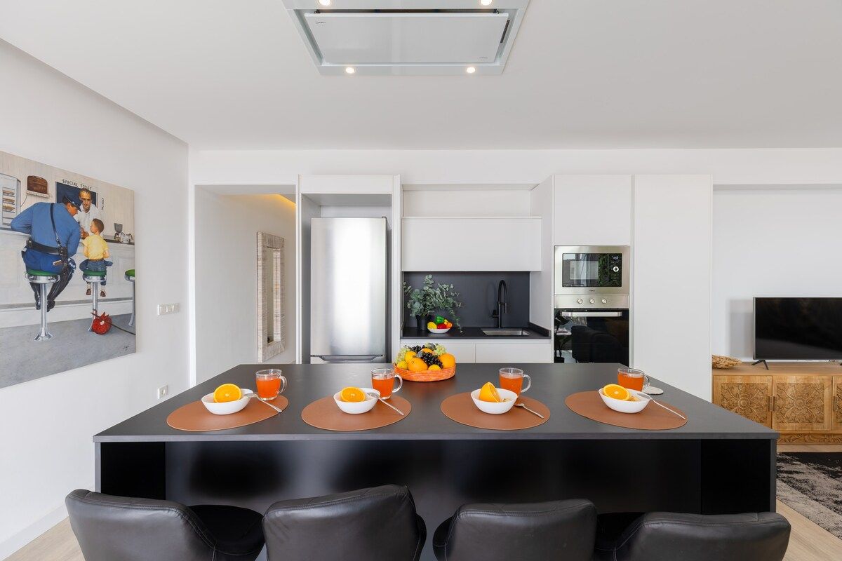Une cuisine moderne avec un coin repas, un téléviseur et un tableau accroché au mur.
