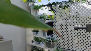 A white outdoor area with a wooden staircase, a white lattice fence, and potted plants on shelves. - Quite Suburbs of Bridgeport  (Portmore)