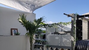 A rooftop garden with potted plants, a barbecue grill, and a white lattice fence. - Quite Suburbs of Bridgeport  (Portmore)