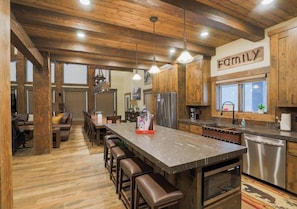 A spacious kitchen with wooden cabinets, a large island with stools, and a 'FAMILY' sign on the wall.