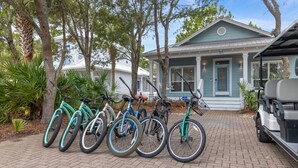 En rad cyklar står parkerade framför ett hus med en veranda och ett garage.