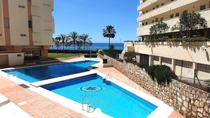 A hotel with a pool area, a view of the ocean, and a palm tree-lined walkway. - Magnificent 10th-Floor Studio with Sea Views (Marbella)