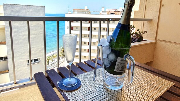 A balcony with a bottle of champagne, a glass, and a plant. - Magnificent 10th-Floor Studio with Sea Views (Marbella)