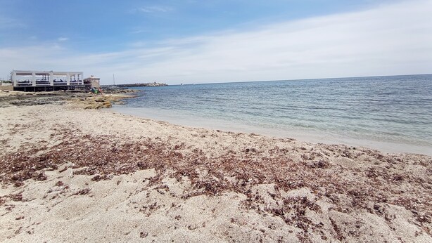 A beach with a building structure, clear sky, and calm sea. - Marina di Leuca Apartment (Marina di Leuca)