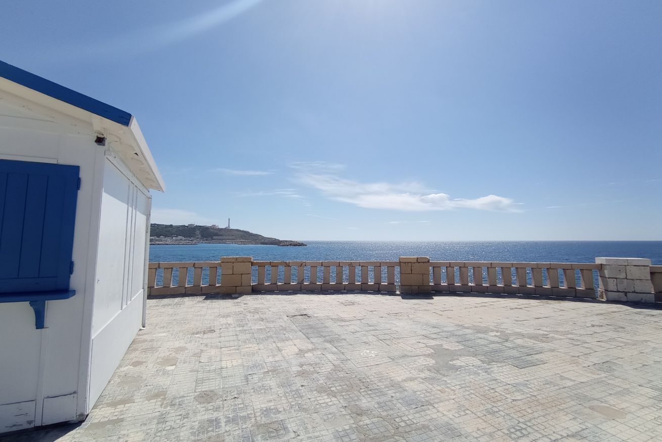 A seaside terrace with a view of the ocean and a distant island.