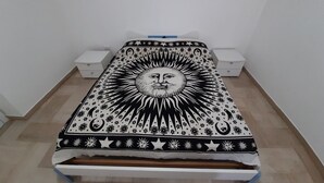 A bed with a black and white patterned bedspread, two bedside tables, and a wooden floor. - Studio apartment Marina di Leuca (Marina di Leuca)