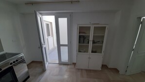 A kitchen with a stove, a cabinet, and a door leading to a balcony. - Studio apartment Marina di Leuca (Marina di Leuca)