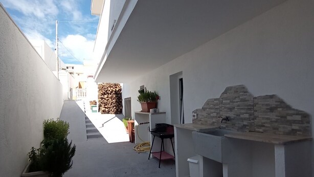 A narrow outdoor corridor with a barbecue area, potted plants, and a stone wall. - Studio apartment Marina di Leuca (Marina di Leuca)