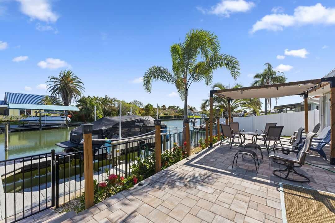 A patio area with a grill, seating, and a view of a body of water.