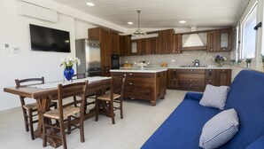 A modern kitchen with wooden cabinets, a central island, and a dining area with a table and chairs.
