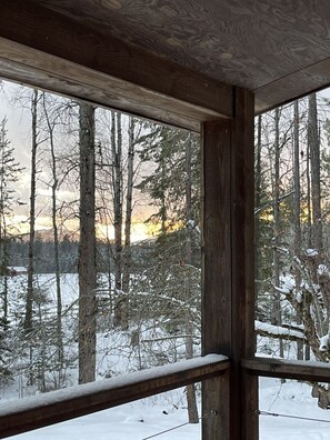 A wooden cabin with a large window overlooking a snowy forest. - The Little House in the woods (Sagle)