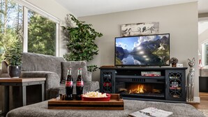 A living room with a fireplace, a television, and a sofa. - The Little House in the woods (Sagle)