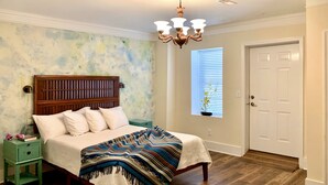 A bedroom with a wooden bed, a green nightstand, a white door, and a window with blinds.