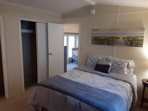 Une chambre à coucher avec un lit, un tableau et une porte donnant sur une autre pièce.