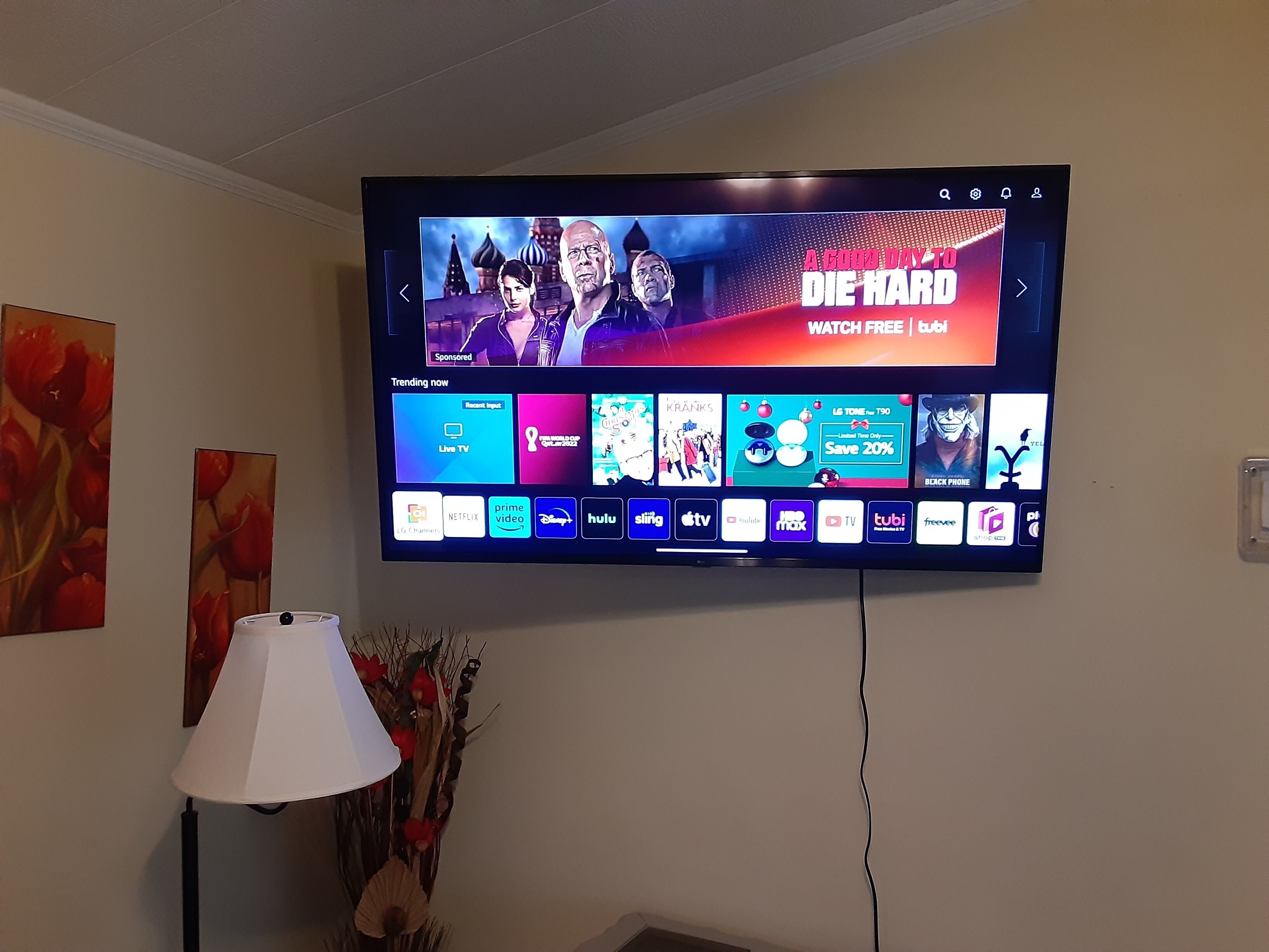 A flat-screen TV mounted on a wall displaying a streaming service interface with various content options.
