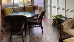 Una veranda coperta con tavolo e sedie, una ventola a soffitto e piante in vaso.
