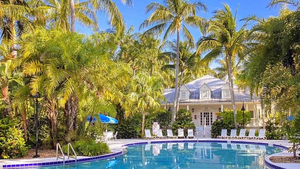 A pool area with lounge chairs, palm trees, and a building with a white facade. - Charming 'Boho Breeze' Retreat w/ Pool Access (Key West)