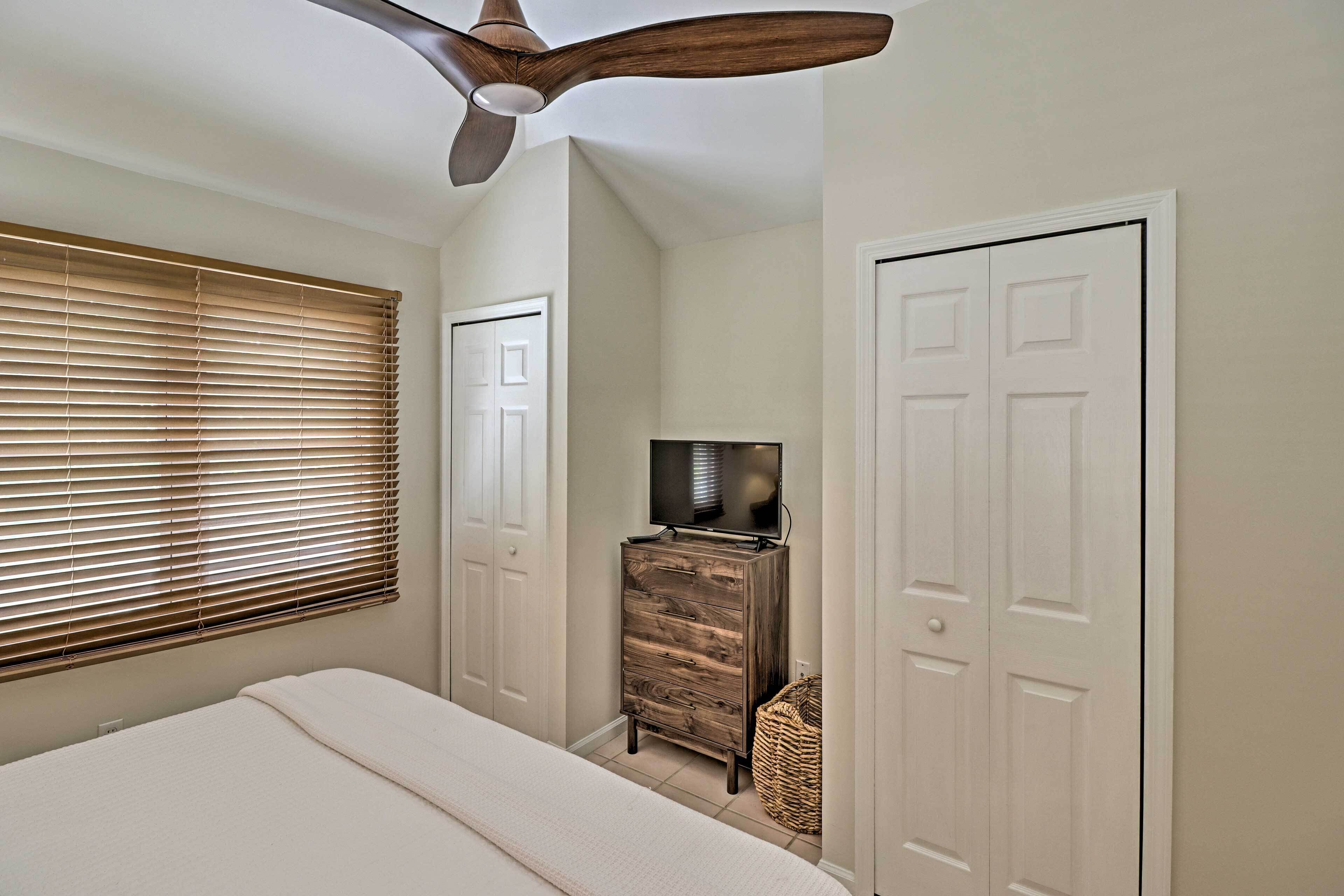 A bedroom with a bed, a dresser, a television, and a ceiling fan.
