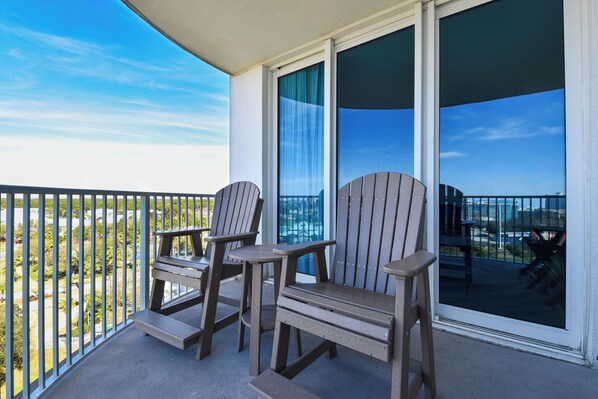 A balcony with two Adirondack chairs and a small table, overlooking a cityscape. - Relaxing Updated Condo w/ Stunning Resort Pool at The Palms of Destin! ππ΄π (Destin)