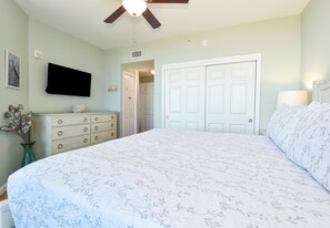 A bedroom with a bed, dresser, TV, and a door leading to another room. - Relaxing Updated Condo w/ Stunning Resort Pool at The Palms of Destin! ππ΄π (Destin)