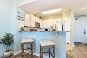 A kitchen with white cabinets, a microwave, a refrigerator, and two bar stools. - Relaxing Updated Condo w/ Stunning Resort Pool at The Palms of Destin! ππ΄π (Destin)