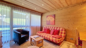 A cozy living room with a leather armchair, a red and yellow checkered sofa, and a wooden coffee table.