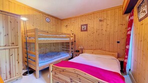 Una habitació de fusta amb lliteres, un escriptori i una làmpada.