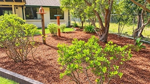 A landscaped garden with mulch, various shrubs, and a bird feeder.