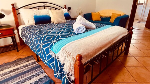 A bed with a geometric patterned bedspread, a blue and white throw blanket, and a wooden headboard.