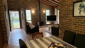 Ein gemütliches Wohnzimmer mit Kamin, Fernseher und Essbereich mit Tisch für vier Personen.