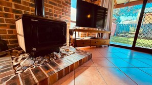A fireplace with a TV on top, a wooden cabinet, and a view of a backyard through a glass door.