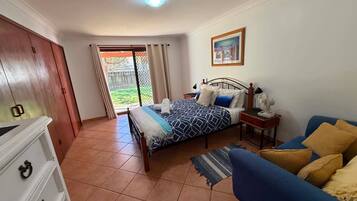 A bedroom with a bed, bedside table, lamp, and a view through a window.