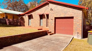 A brick building with a red garage door, a covered porch, and a small brick wall.