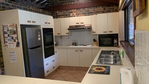 Eine Küche mit weißen Schränken, einem Edelstahl-Kühlschrank, einem Backofen, einer Mikrowelle und einem Spülbecken.