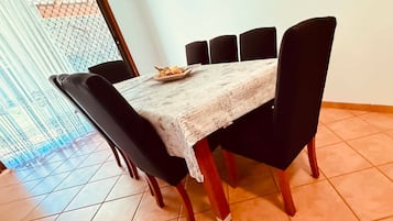 Una mesa de comedor con mantel estampado, rodeada de sillas negras.