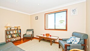 A living room with a bookshelf, two armchairs, a coffee table, and a large window.