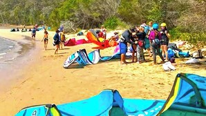 A beach with people and colorful kites.