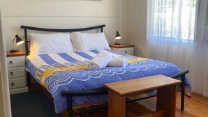 A neatly made bed with a blue and white striped bedspread, two white pillows, and two bedside lamps. - My Hideaway - Pet Friendly (Callala Beach)