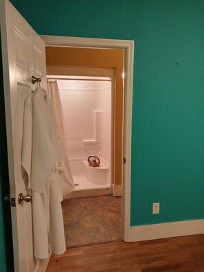 A bathroom with a white bathtub, a towel rack with a white towel, and a wooden floor. - The apARTment/ historic railroad inn, pet-friendly (Cowan)