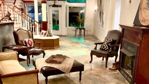 Un salon spacieux où un grand chien est allongé sur le sol, entouré de différents types de sièges et d’une cheminée.