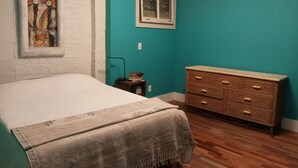Une chambre à coucher avec un lit, une commode, un tableau et une fenêtre.