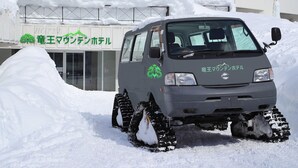 A vehicle with snow tracks parked in front of a building with Japanese signage. - Ryuo Mountain Hotel (Yamanouchi)